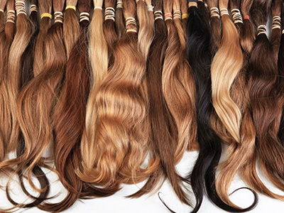 The image shows a collection of hair extensions displayed in rows, with varying shades of blonde and brown hair.