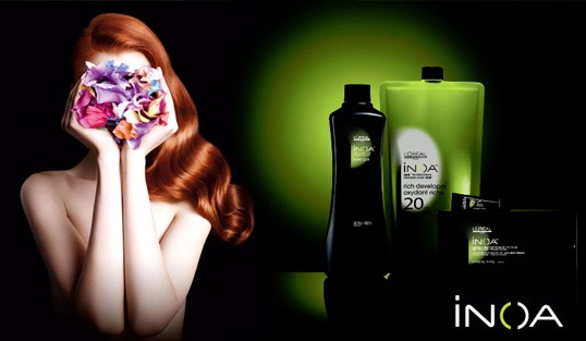 The image displays a woman s face in the foreground, partially obscured by her hand holding a flower. In the background, there is a product advertisement featuring skincare items and packaging with the brand name  INOA.